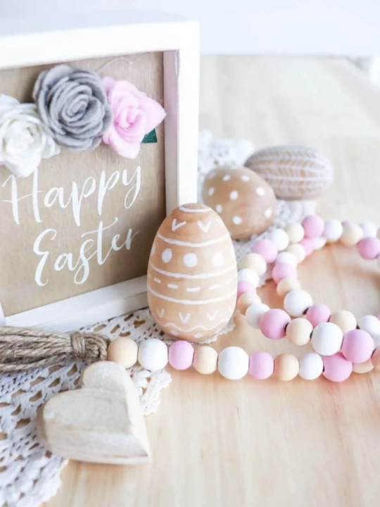 Happy Easter Wooden sign and wooden Painted Eggs on table with a bead garland