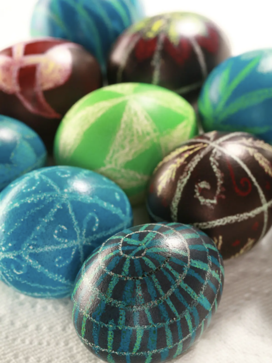 Pysanky Eggs in deep blues, purple, black and bright green on a paper towel.