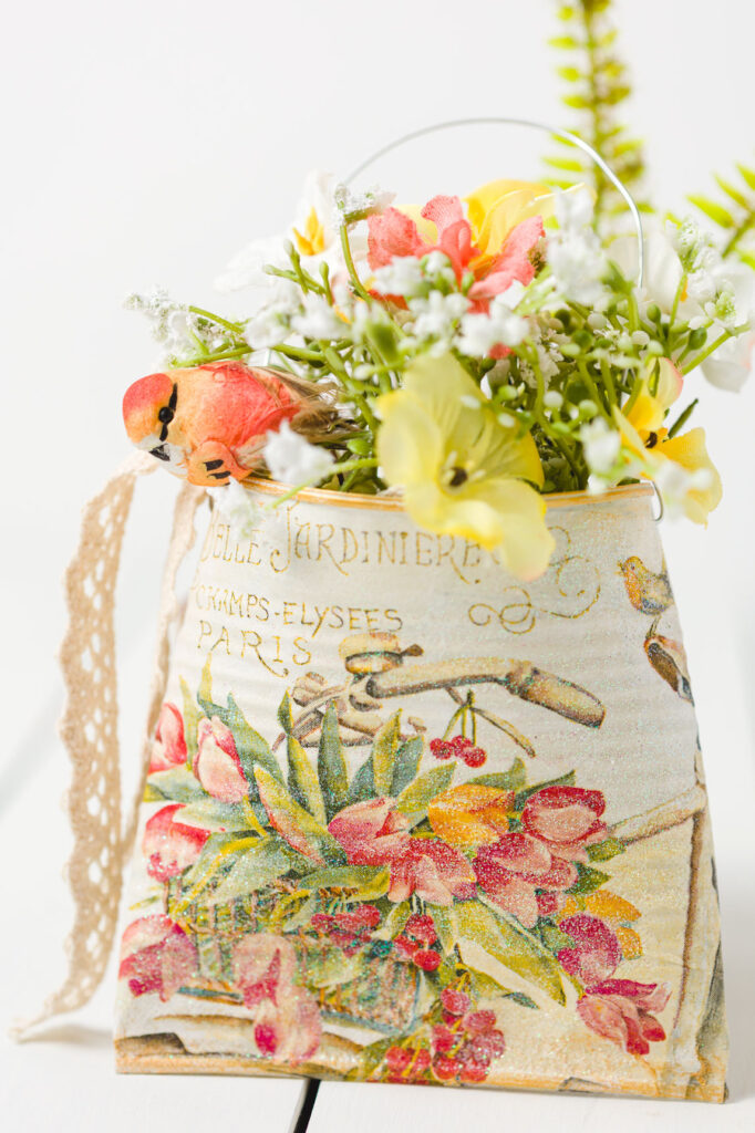 Front view of napkin decoupage can with flowers and a bird on wood table