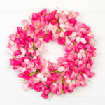 Pink tulip wreath hanging on a white wall