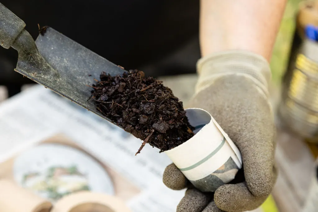 Filling the seed starter pots with soil using a trowel