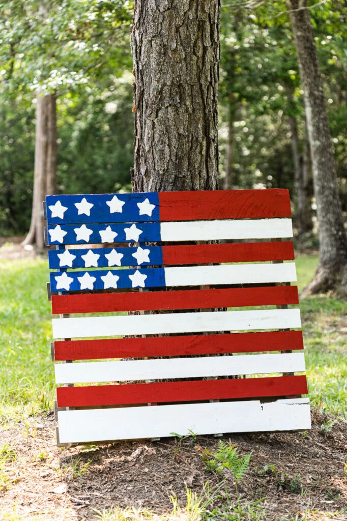 Large flag pallet sign leaning against a tree in the yard