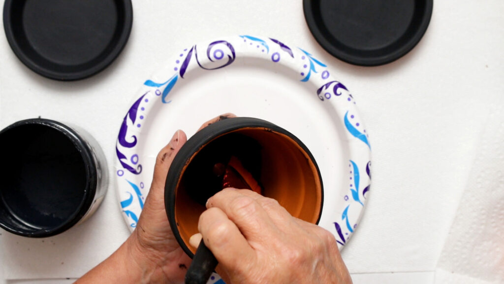 Painting a clay pot with black paint