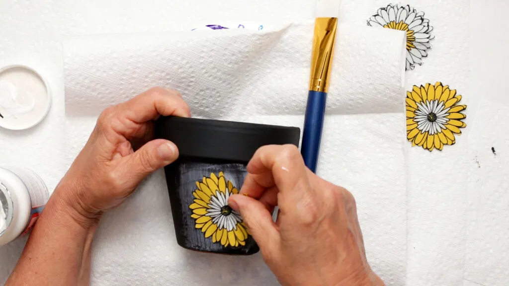 Placing a fabric flower over the wet Mod Podge and pressing it in place