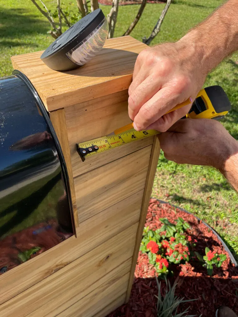 Measuring and marking the solar light placement on the side of the wood mailbox