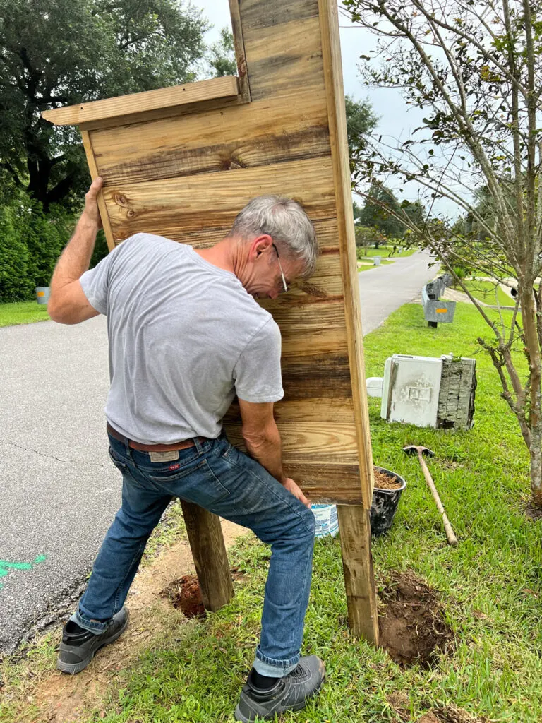 Placing the wooden DIY mailbox assembly into the holes