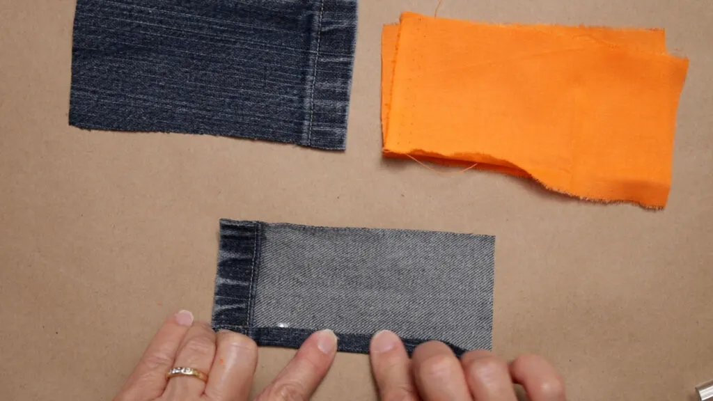 Folding the cut edge of the jean fabric over 