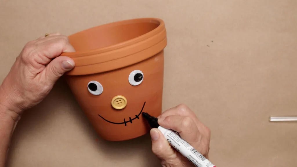 Using a paint market to paint on a scarecrow mouth