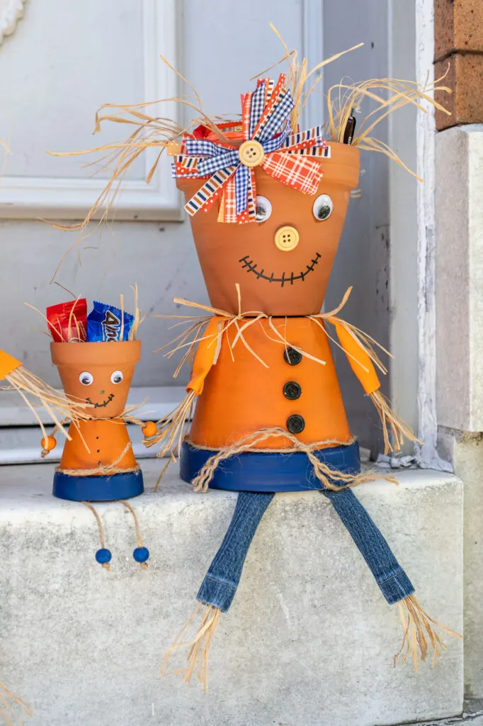 Large and small scarecrows sitting on the porch