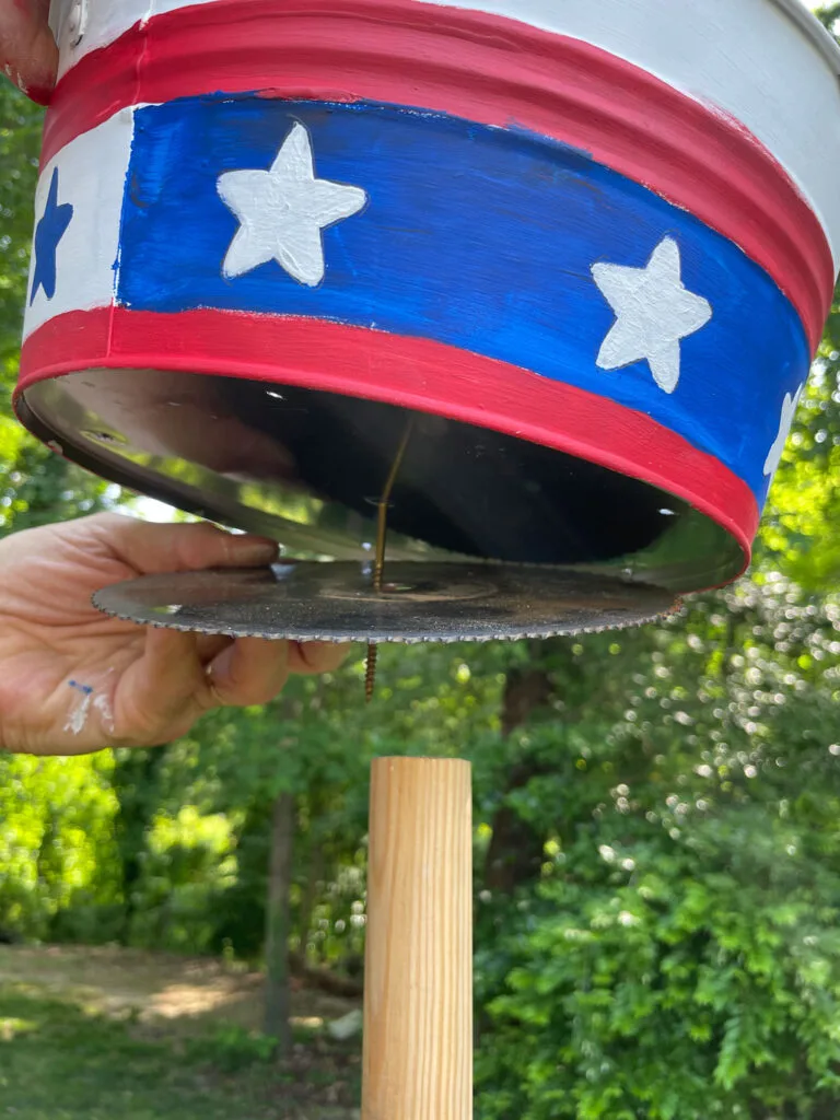 Placing the saw blade under the container and then on the wooden dowel