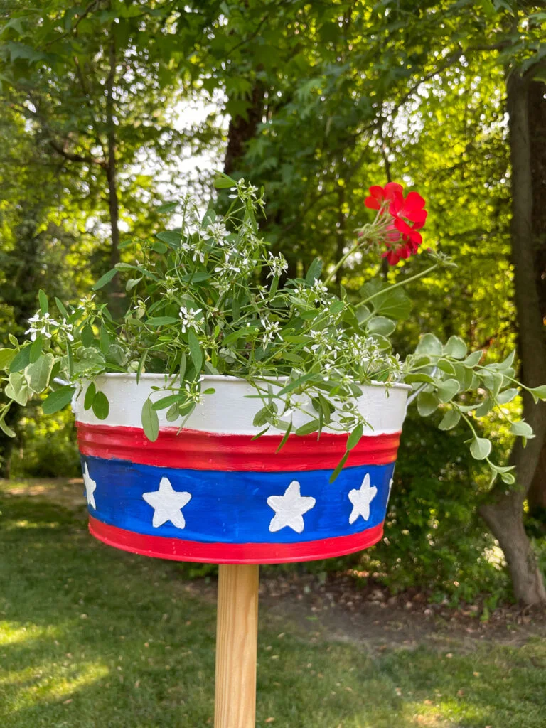 Painted container filled with flowers in the yard