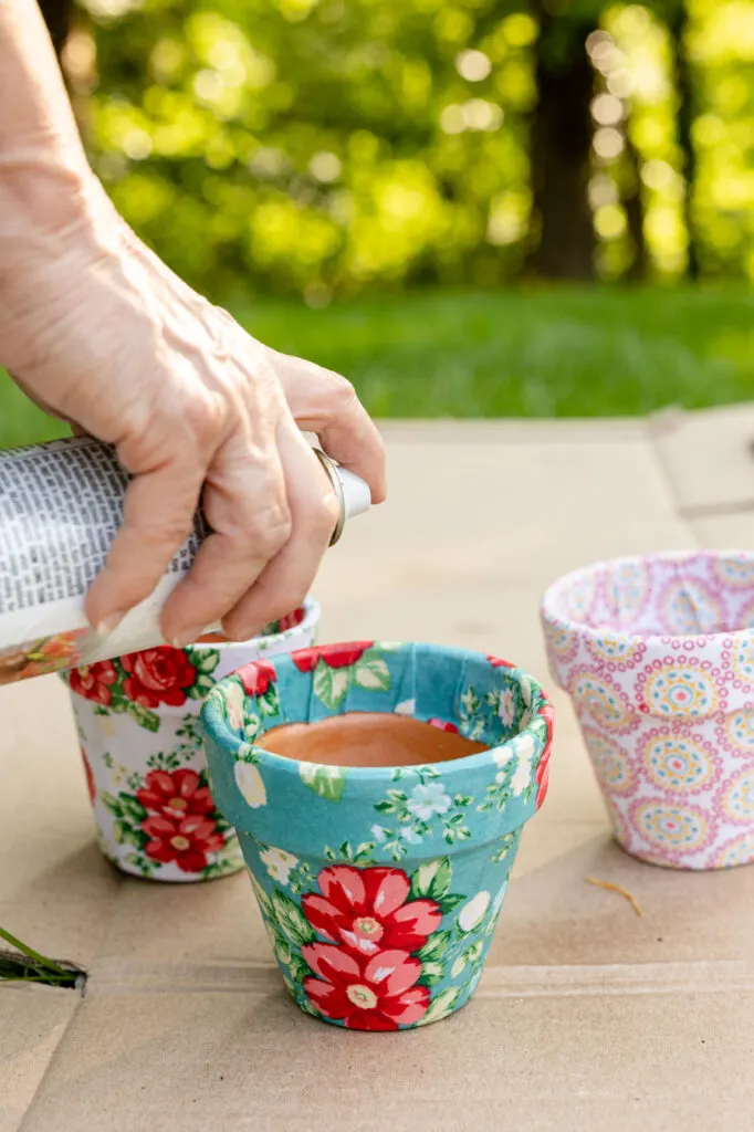 Applying sealer to fabric decoupage clay pots 