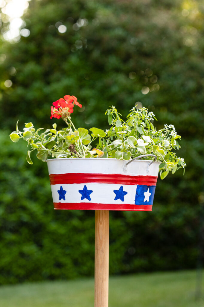 Red, white, and blue DIY planter filled with flowers on a post 