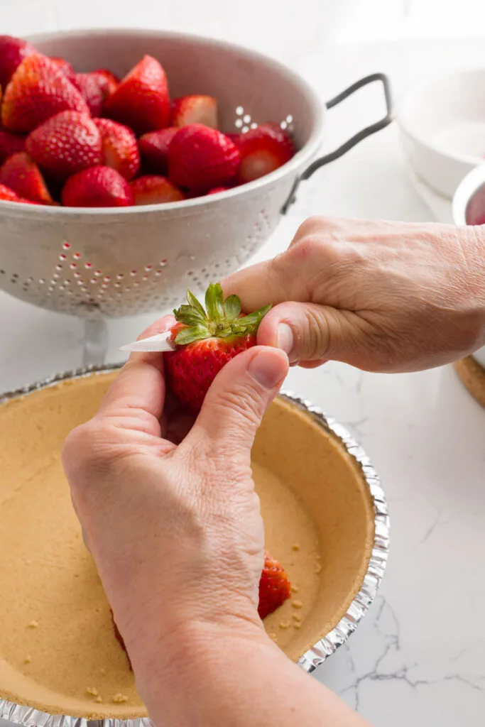 Cutting up the strawberries over the pie crust
