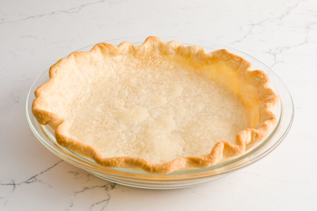 A baked pie crust in a glass pie plate 