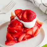 Slice of Strawberry Pie with Kool whip and a strawberry on top