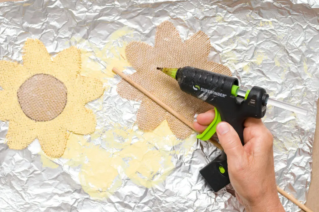 Applying glue to fabric flower back piece 