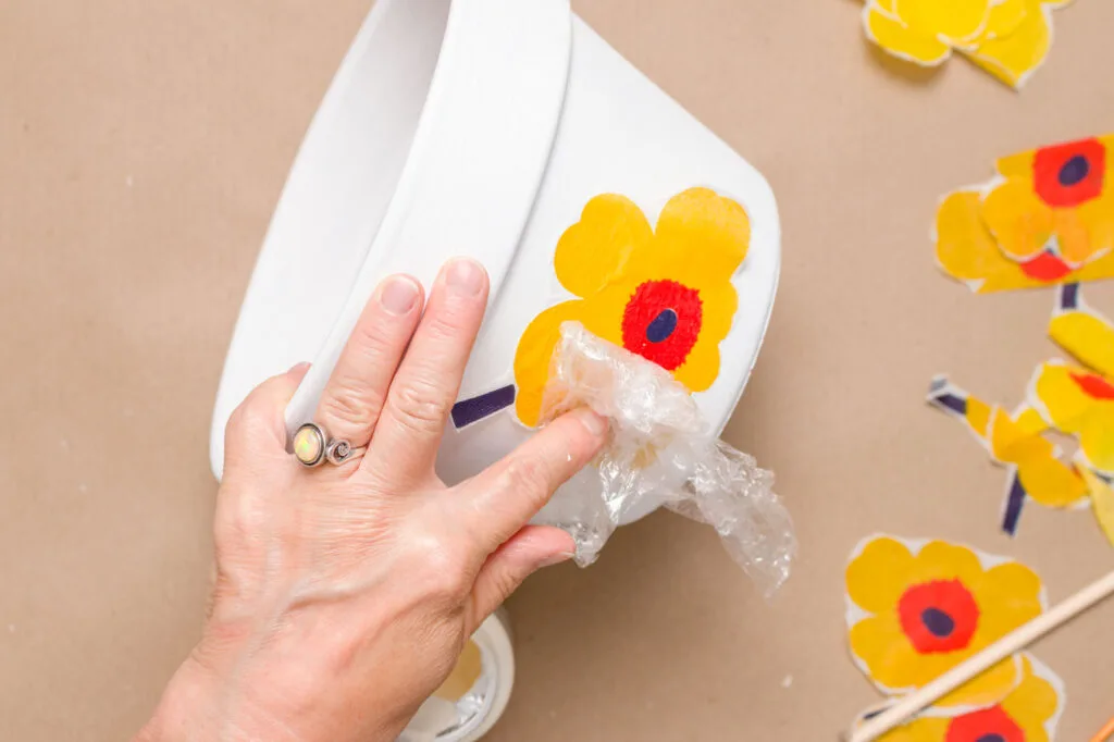Using plastic wrap to smooth on the paper flower on the pot