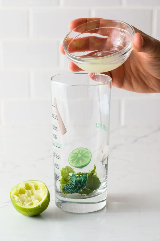 Mint leaves and fresh lime juice in a glass