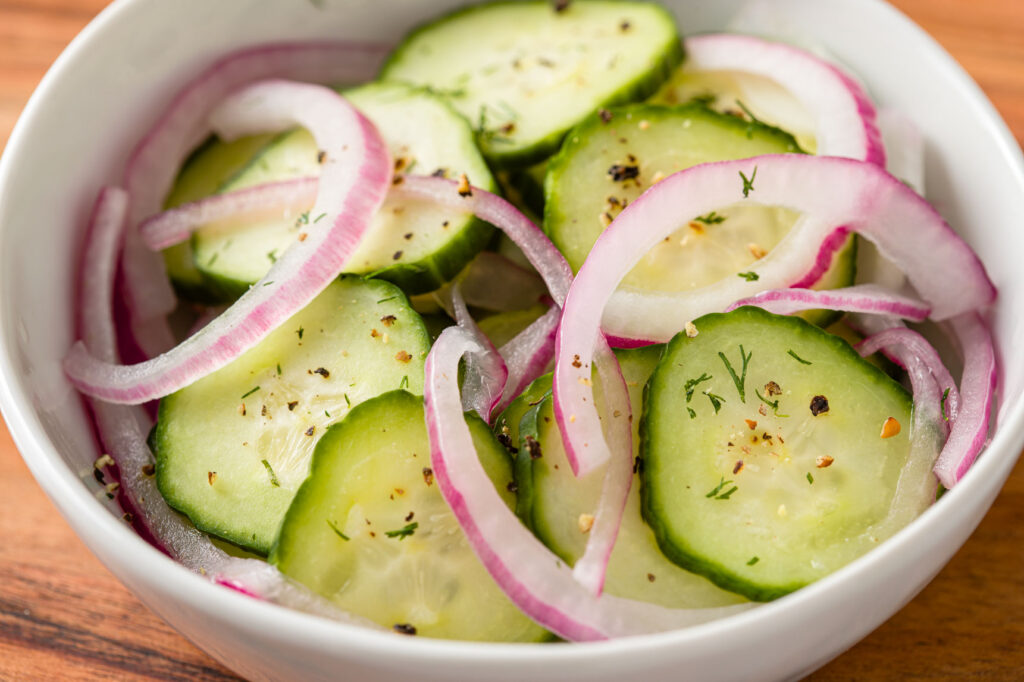 Bowl filled with cucumber salad on a wood table