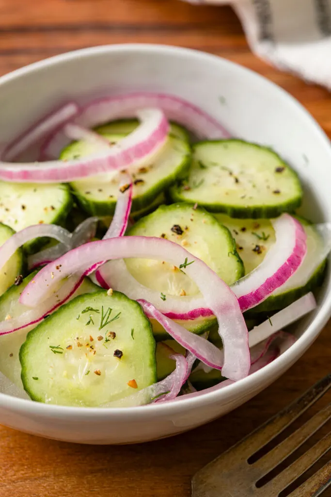 Red onion and cucumber salad in a bowl on a wood table