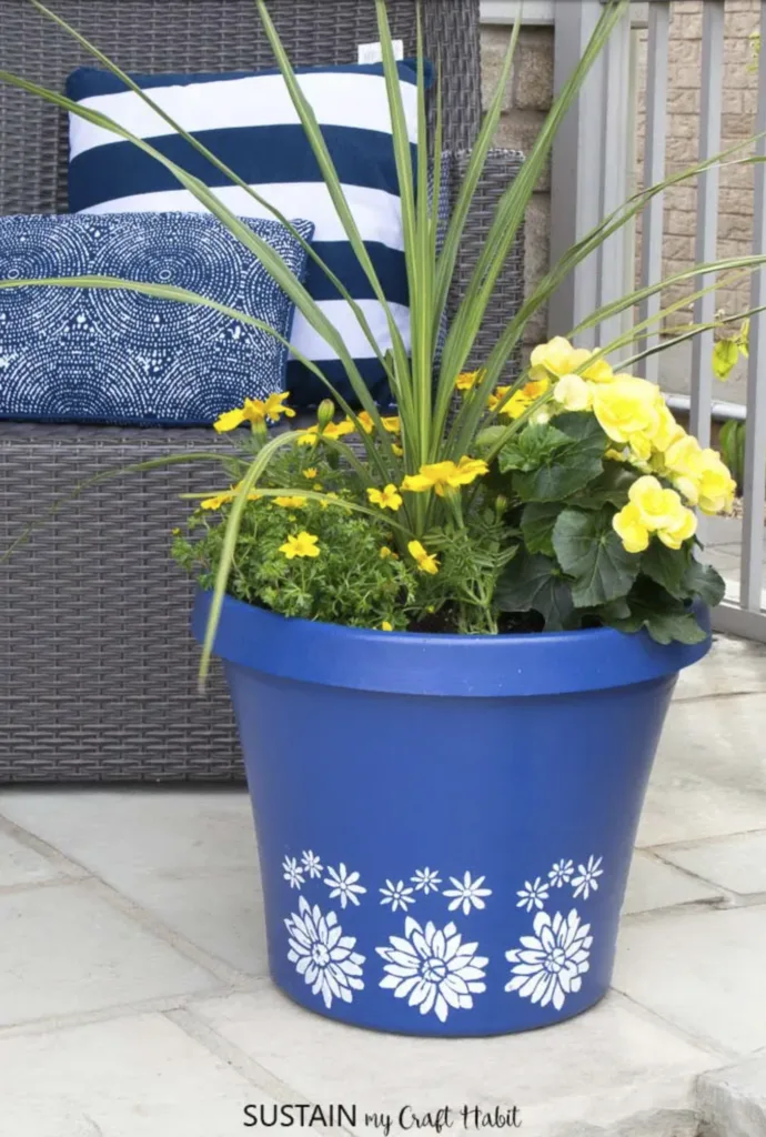 blue planter with white flowers filled with yellow flowers on a porch