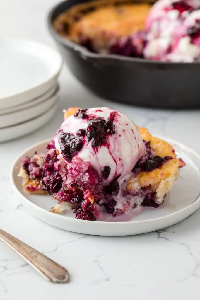 Blackberry cobbler topped with ice cream with blackberry syrup