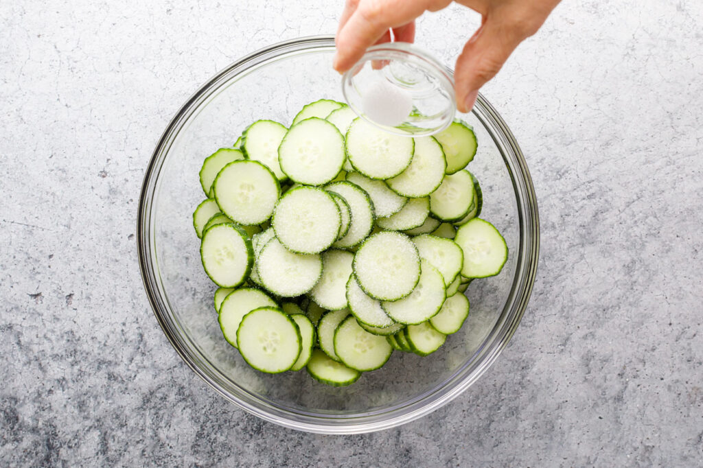 sprinkling salt over the cucumber slices