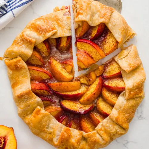 peach galette with a slice cut out on a table