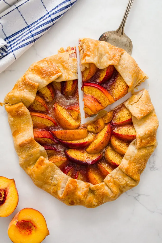 Peach Galette peach galette with a slice cut out on a table