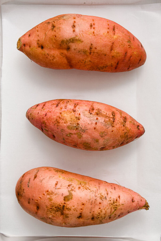 sweet potatoes on a sheet pan lined with parchment paper 