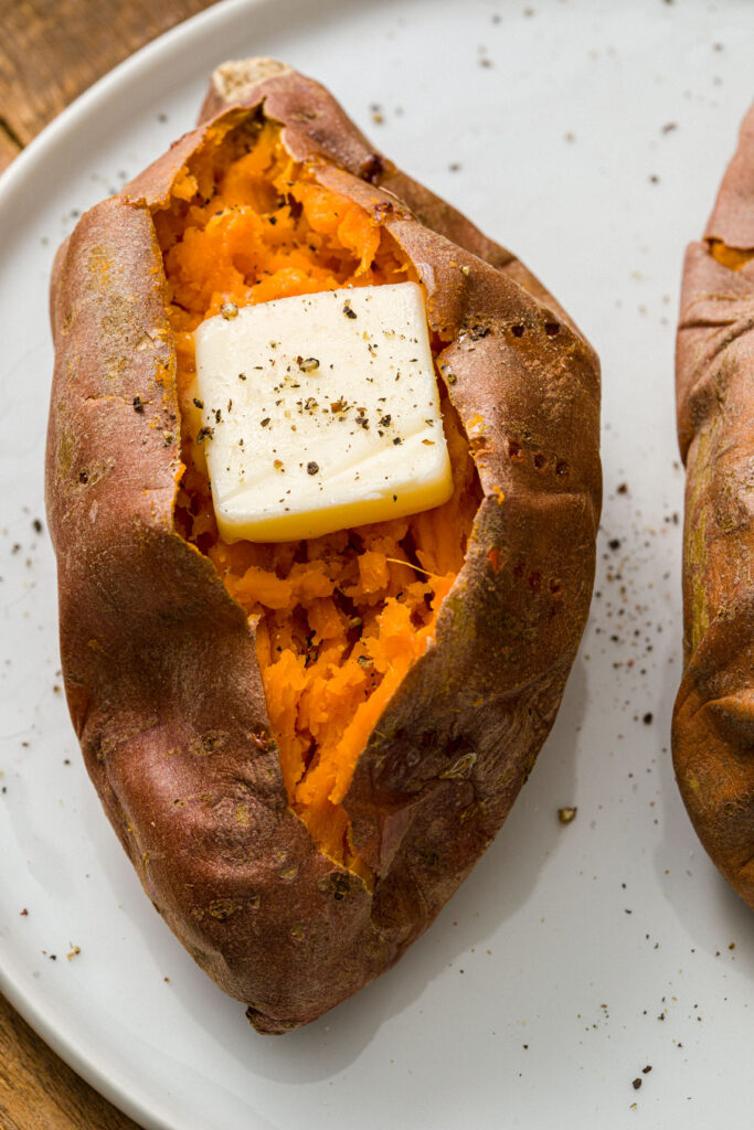 Baked sweet potato with butter and seasoned with salt and pepper