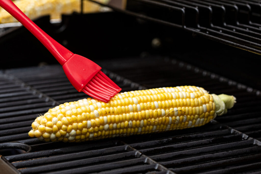 Brushing oil on corn on the grill