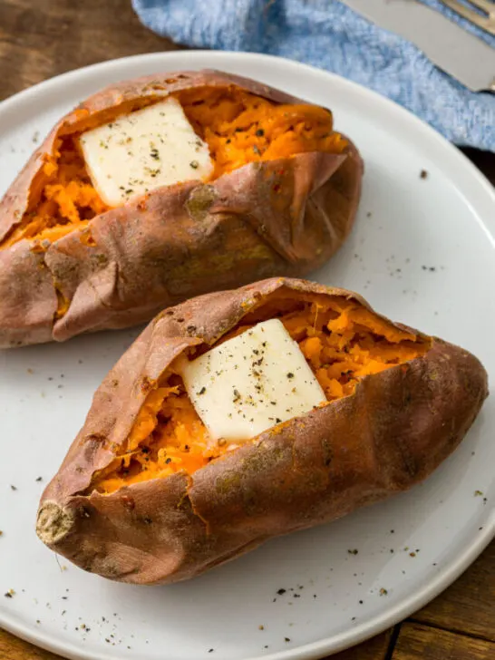 two baked sweet potatoes with butter on a plate