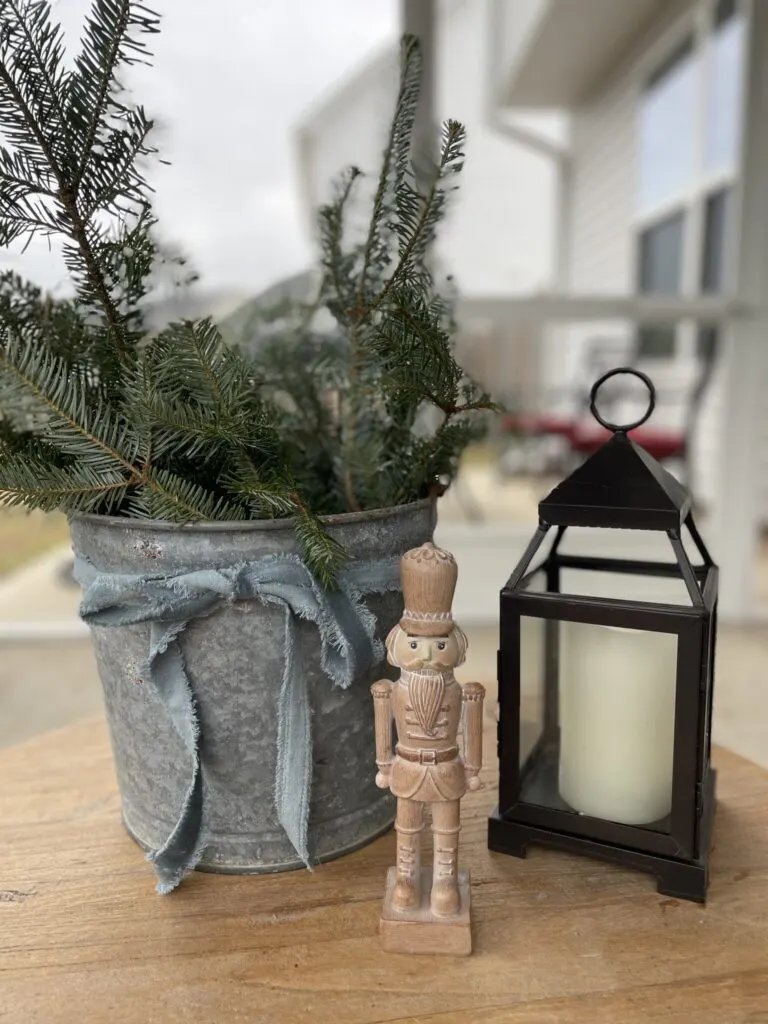 Bucket filled with pine branches with a velvet bow, wooden soldier, and lantern  