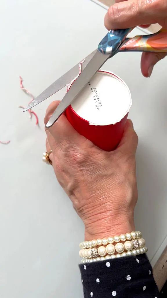 cutting the edge off a paper cup with scissors