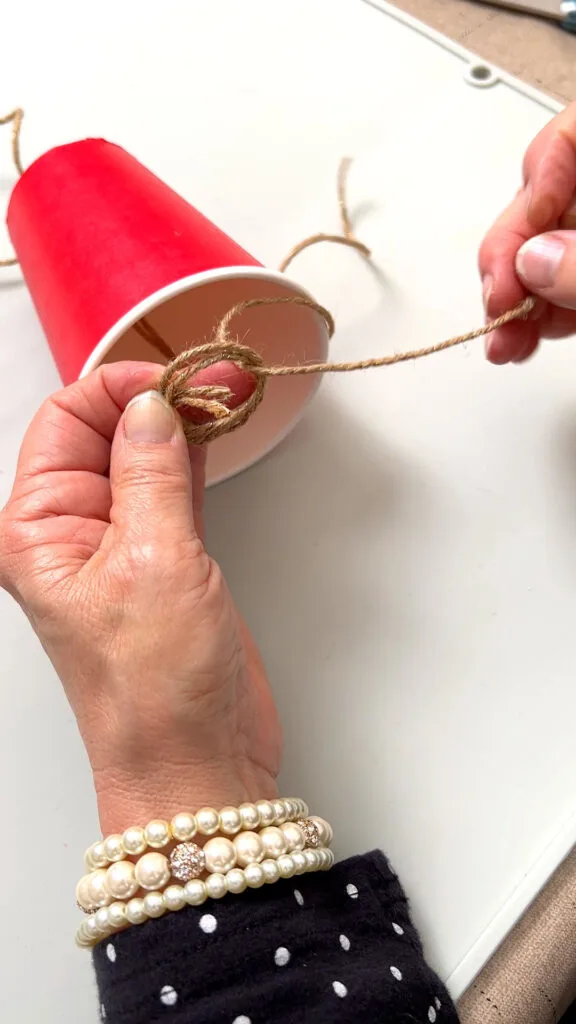 pulling the jingle bell twine through the hanger loop knot