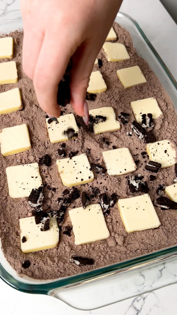 topping the cake with chopped Oreos