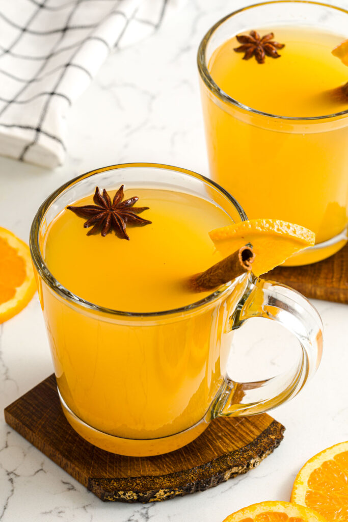 two mugs of Wassail with a garnish of cinnamon sticks and stair anise