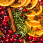 Pot filled with fresh cranberries, orange slices, rosemary, cinnamon sticks, nutmeg, cloves, star anise and water