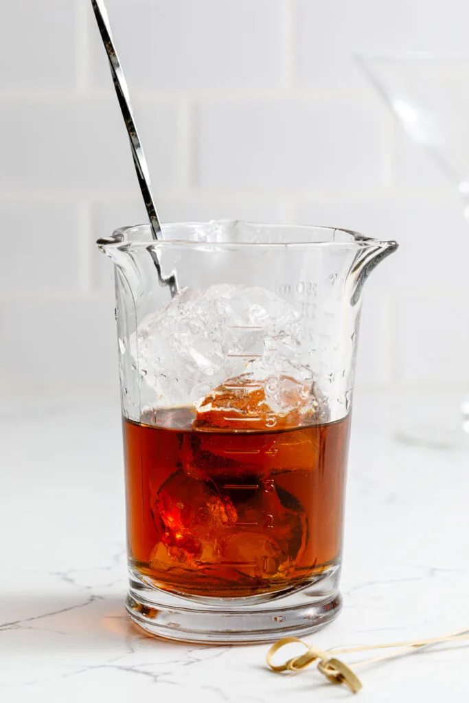 Manhattan cocktail in a glass with ice and a spoon