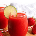 A strawberry daiquiri in a stemless wine glass with a wheel of lime on the rim