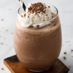 Frozen hot chocolate in a glass with a straw on a coaster