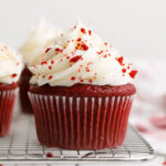 Red velvet cupcakes with frosting on a cooling rack