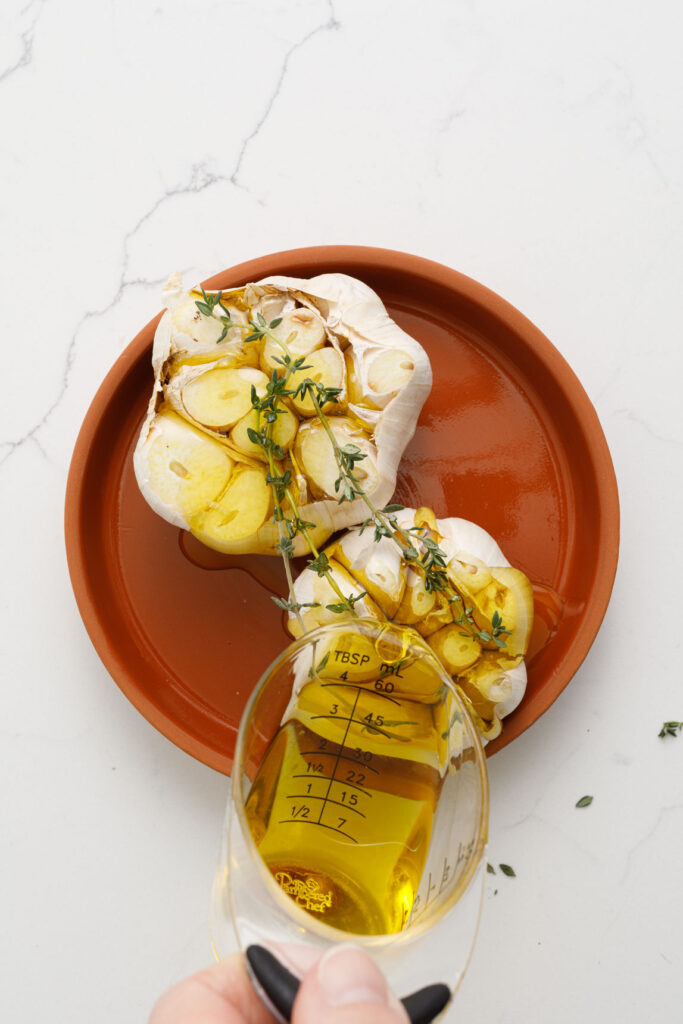 pouring oil over garlic heads