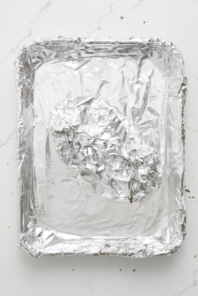 tin foil lined pan with foil wrapped garlic