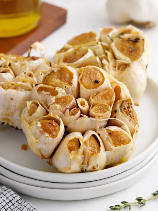 three garlic heads on a stack of plates