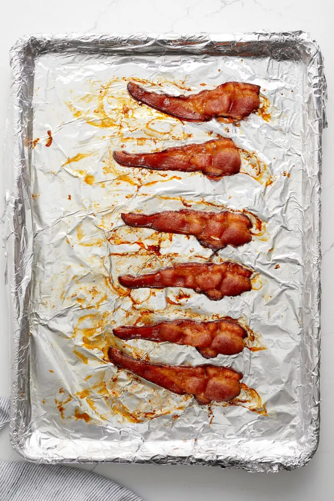 crispy baked bacon on a foil lined baking sheet