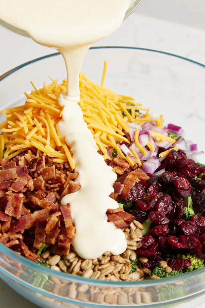 Pouring salad dressing over broccoli mixture