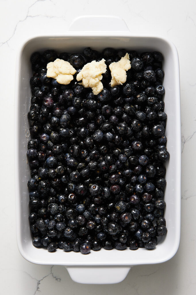 Dots of cobbler dough on the blueberries